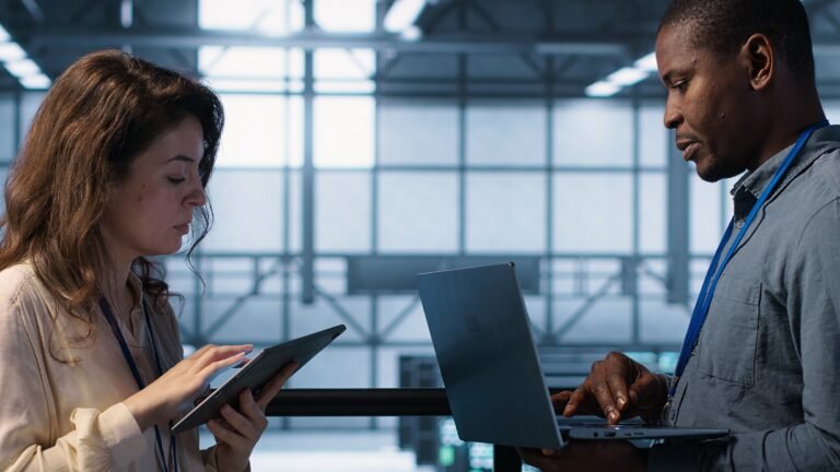 Team of technicians working in server farm, using laptops to analyze data